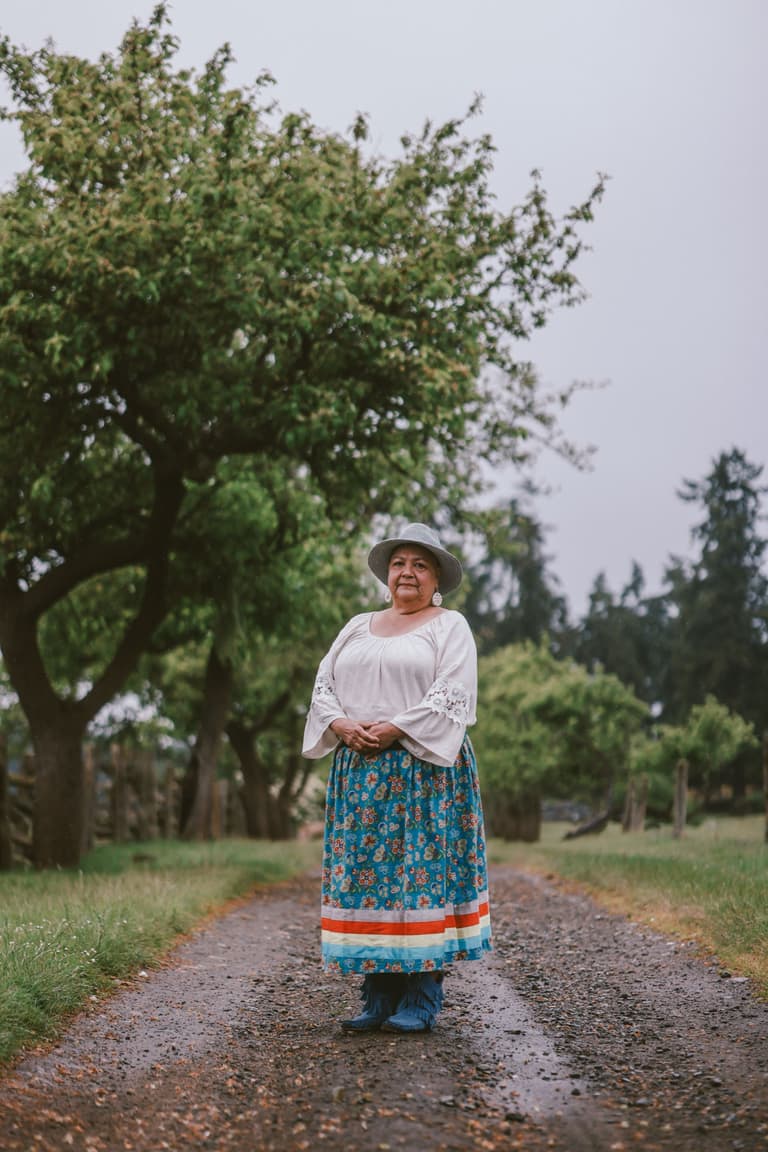 A woman in a ribbon skirt on an orchard lane