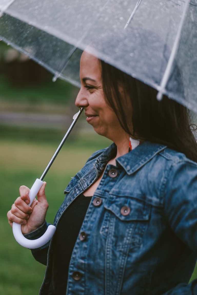 A woman smiling under a clear umbrella in the rain