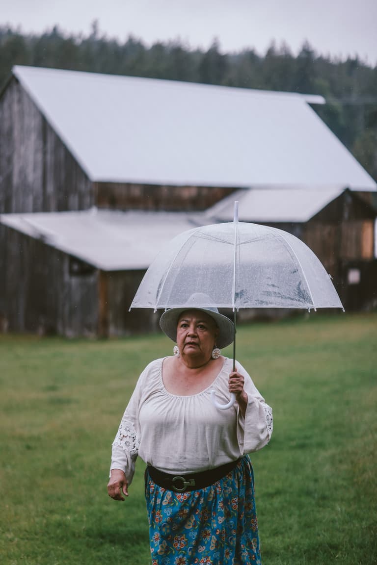 A woman walking away down a farm track under an umbrella