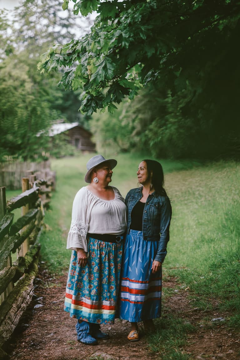 Two women walking together beside a fence line