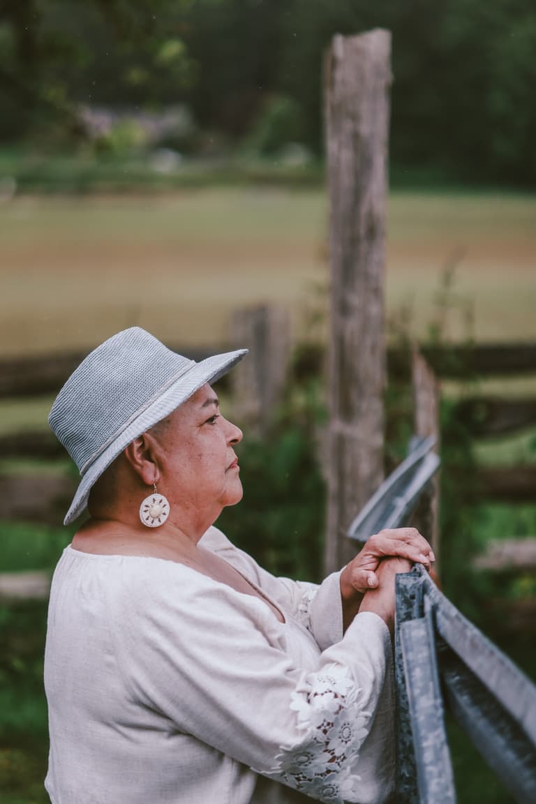 Two women walking side by side along a fence line