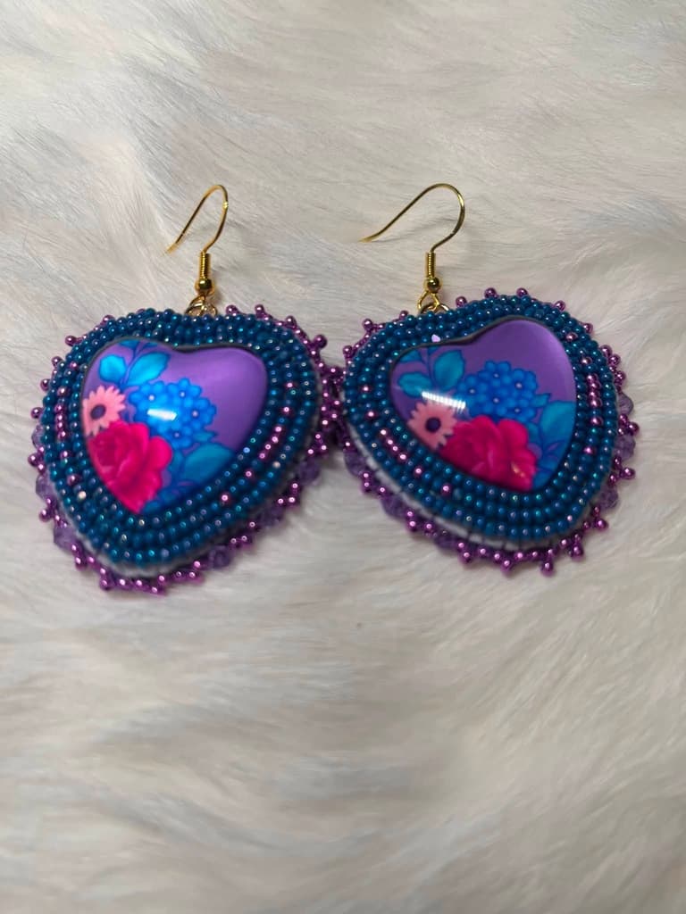 Heart shaped beaded earrings in teal and violet around a floral cabochon