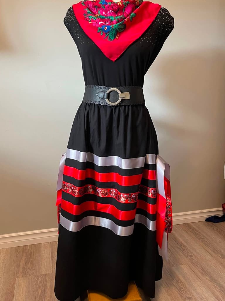 Black cotton ribbon skirt with red and white satin ribbons and a printed floral band, worn with a red shawl